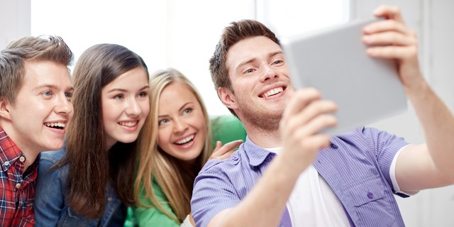 education, people, friendship, technology and learning concept - group of happy high school students or classmates with tablet pc computer taking selfie in classroom