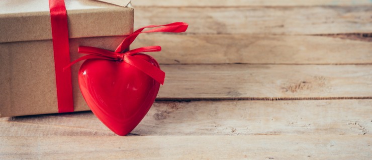 Gift box and red heart on wood table with space